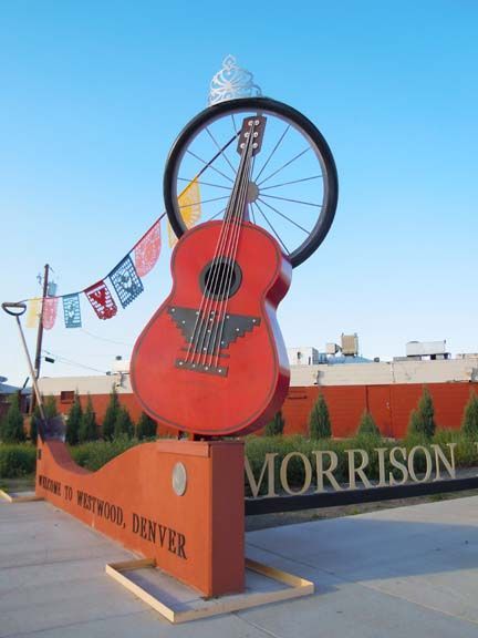 Large red guitar sculpture in Morrison, with a bike wheel above and flags beside it.