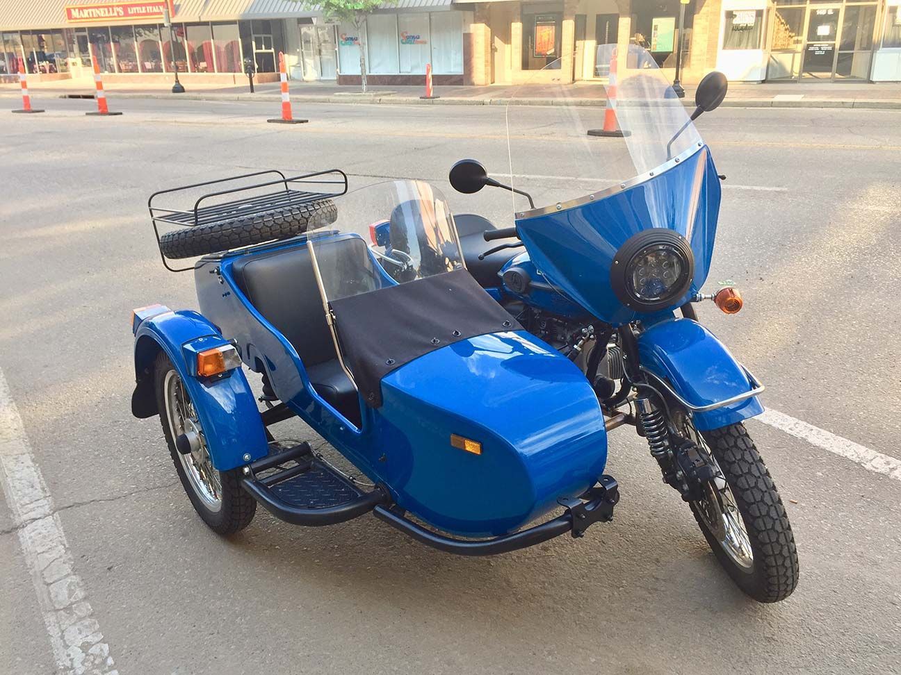 Blue motorcycle with sidecar parked on a street near traffic cones and buildings, Salina, Kansas