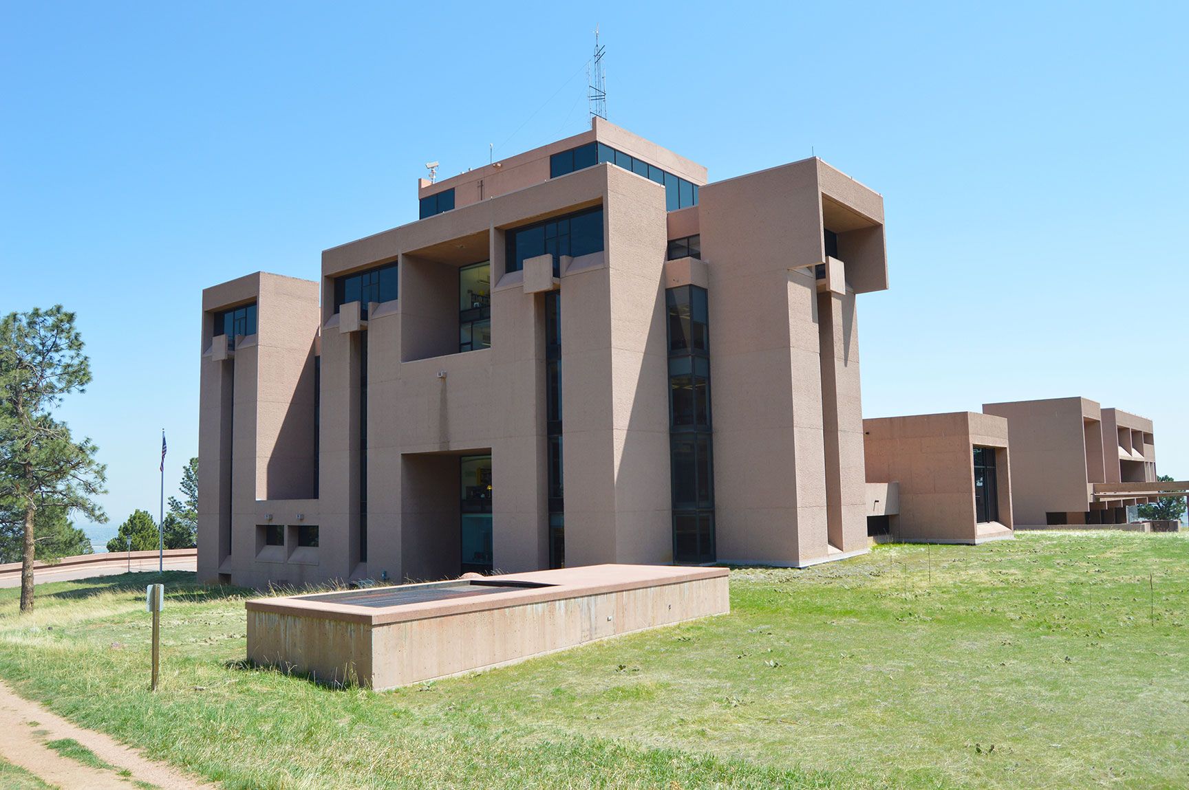 Modern tan apartment building with balconies on a grassy lawn under a blue sky