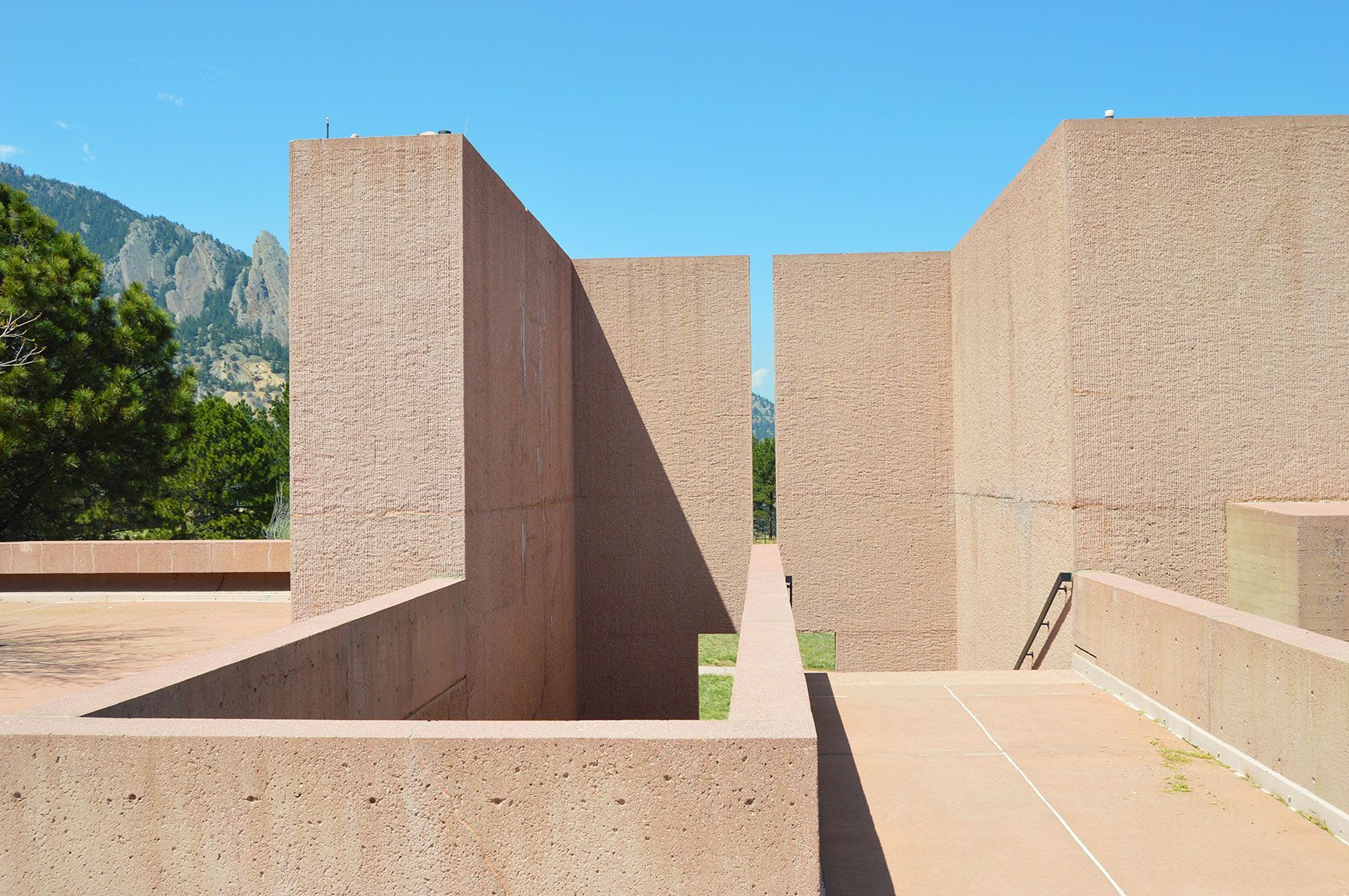 Sunlit stone courtyard with geometric walls and a mountain backdrop