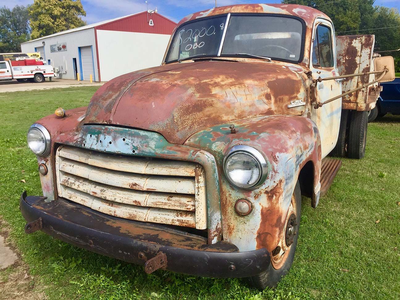 Rusty old pickup truck parked on grass, front view with peeling paint and weathered body, Salina, Kansas