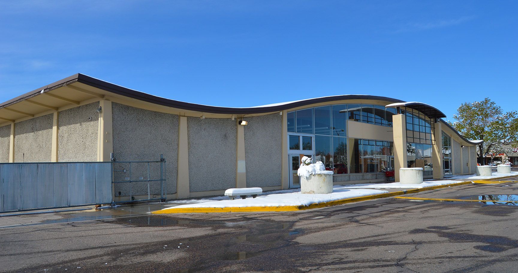 Snowy modern building entrance with blue awning and brick exterior under a clear sky