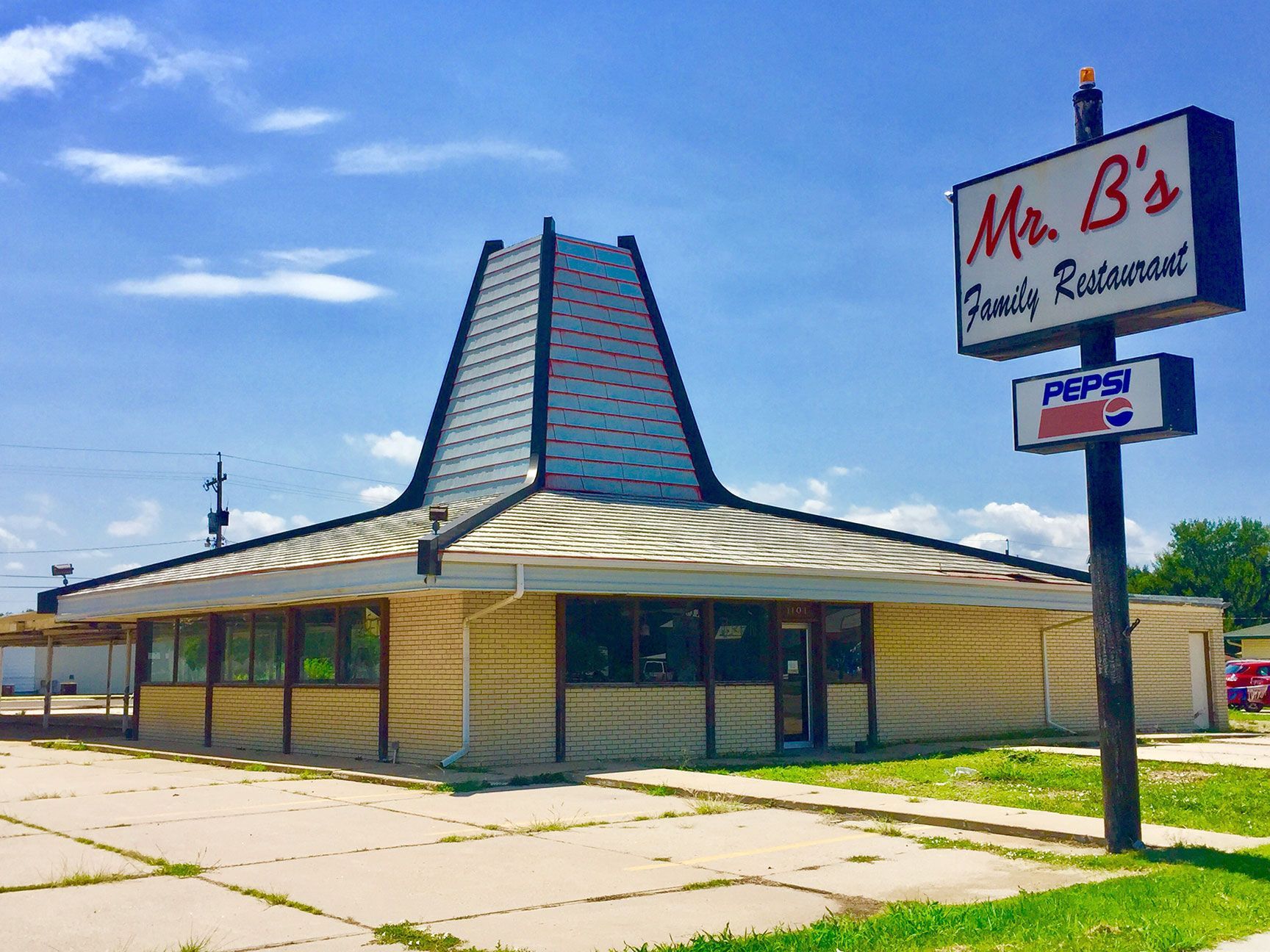 Retro roadside diner with a tall sign and teal tower roof under a blue sky