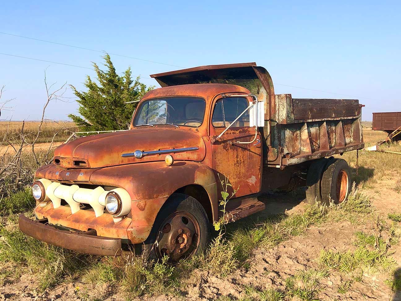 Rusty old pickup truck parked in a dry field under a clear blue sky, Salina, Kansas