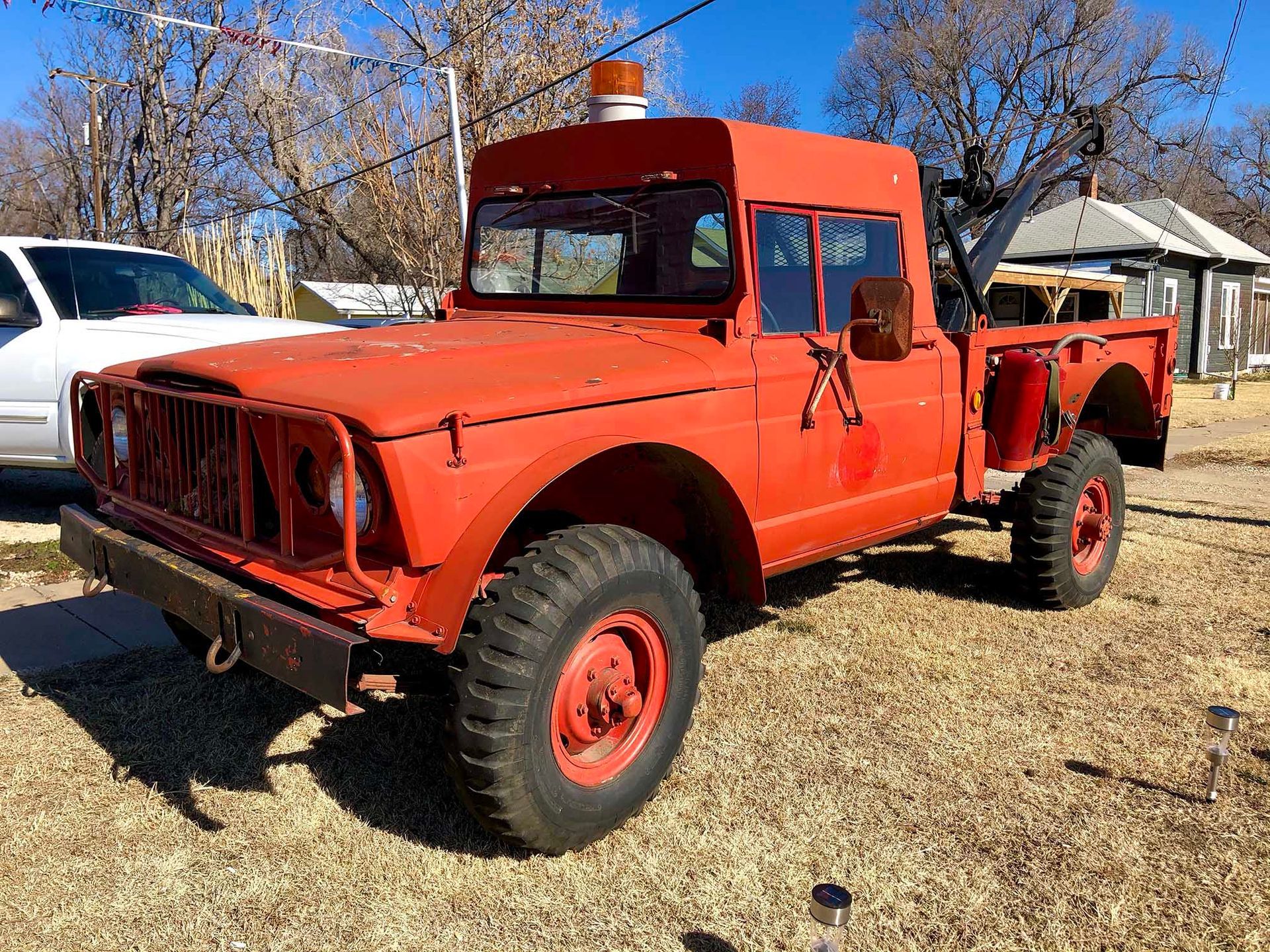 Red vintage off-road truck parked outdoors on grass under a clear blue sky, Salina, Kansas
