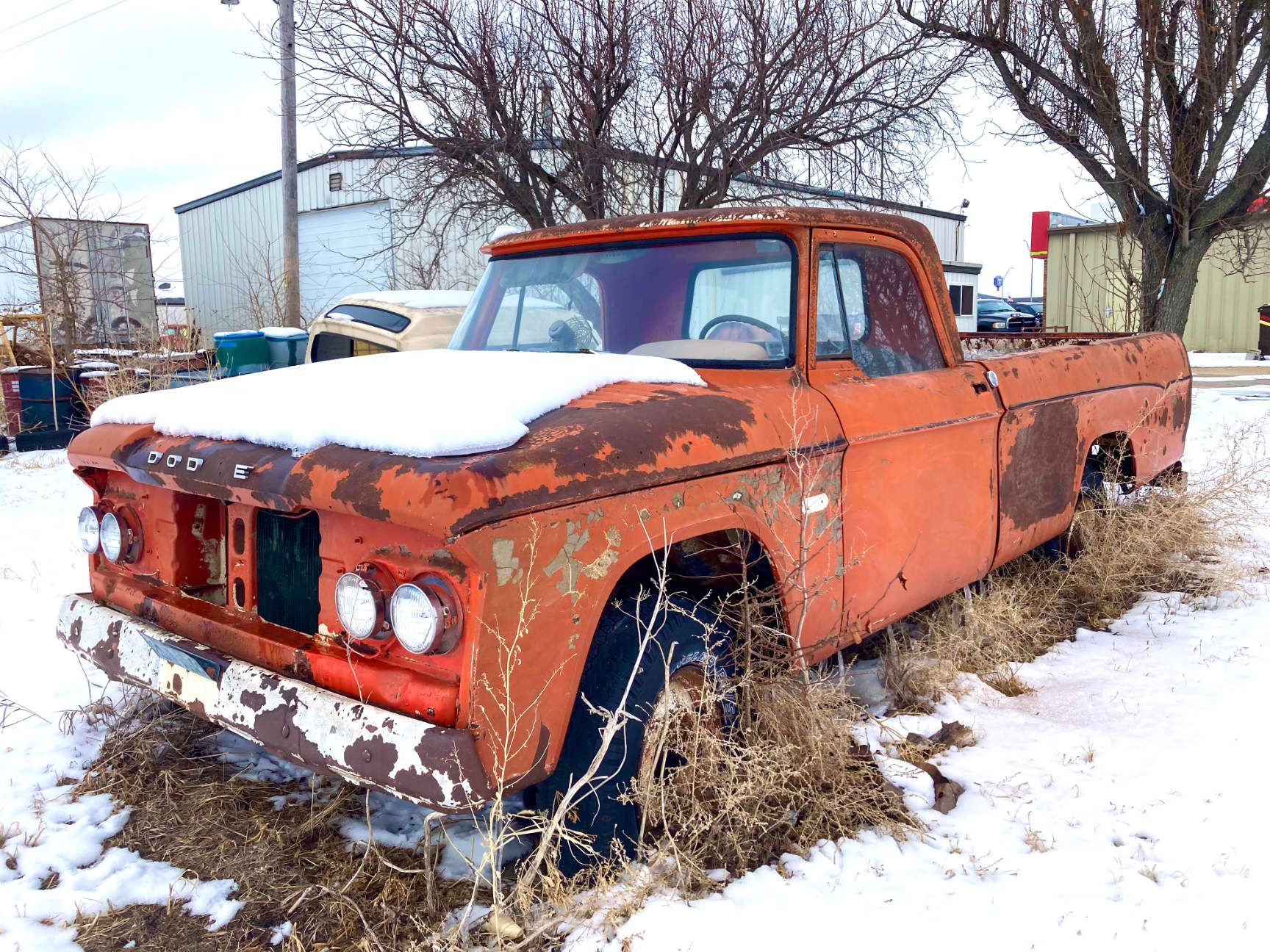 Rusty orange pickup truck buried in snow, parked outdoors in winter. York, Nebraska. 