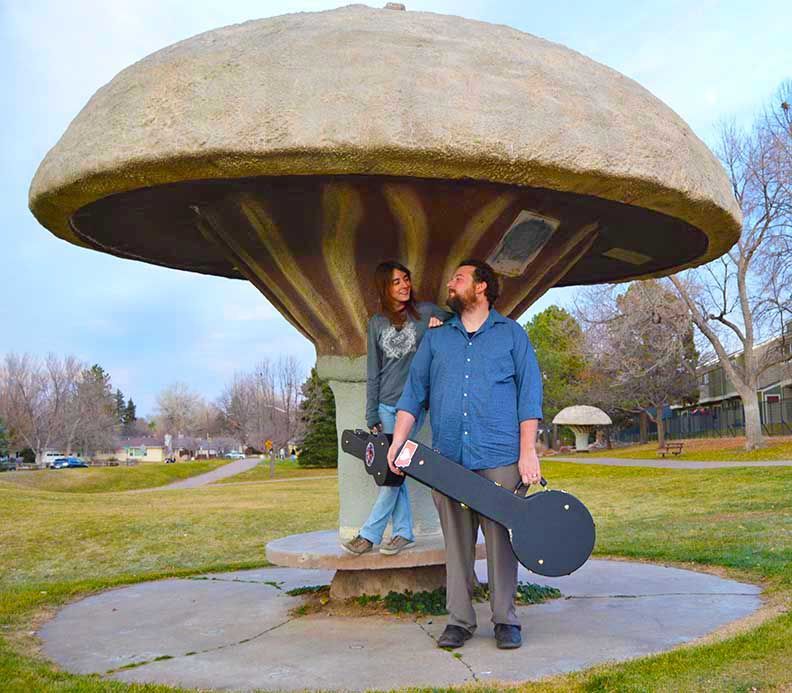 Pickin' Pear pose beneath a giant mushroom sculpture in a park, Englewood, Colorado