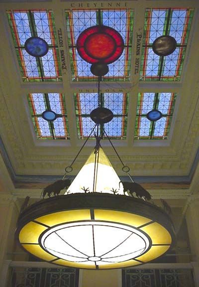 Stained-glass ceiling with colorful circular panels above a hanging round chandelier.