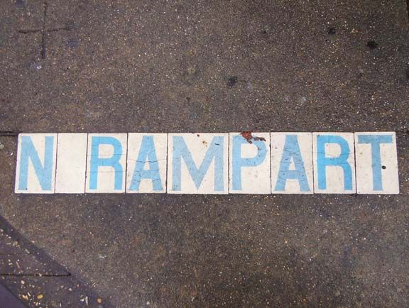 Blue-and-white letters spelling “NRAMPART” on dark pavement