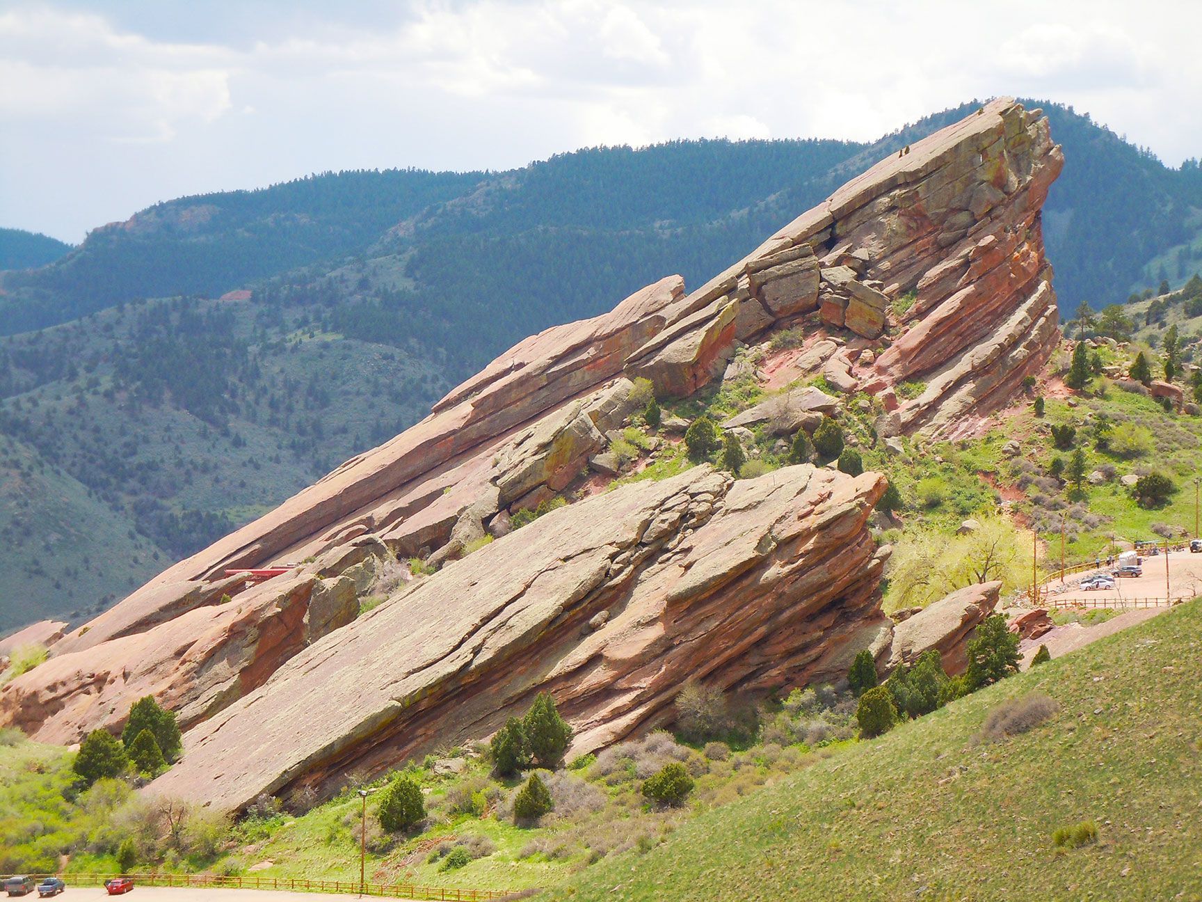 Tilted red rock slabs in a green mountain landscape under a clear sky, Red Rocks, Morrison, Colorado
