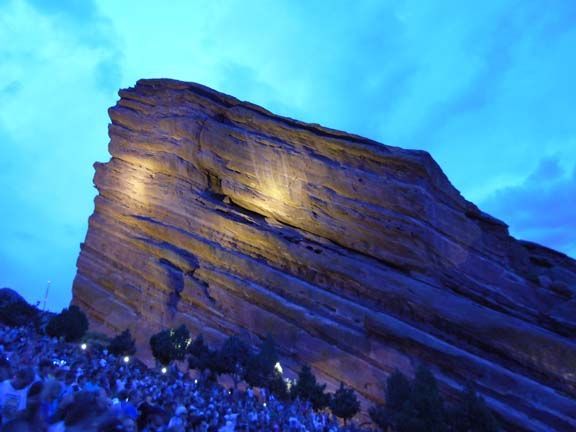 Illuminated sandstone rock formation at dusk under a blue sky