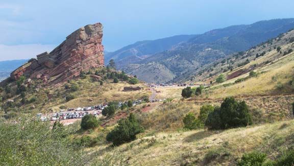 Rocky red cliff above a green mountain valley under a clear blue sky