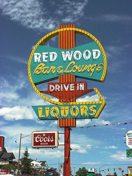 Vintage roadside sign for Redwood Bar & Lounge and Drive-In Liquors against a blue sky