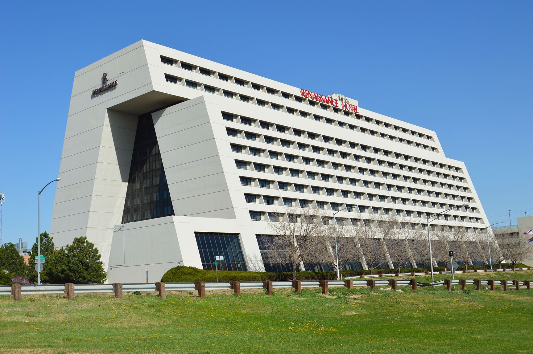 Modern angular hotel building with rows of windows beside a grassy lawn under a clear blue sky, brutalist architecture, Renaissance Hotel, Denver, Colorado