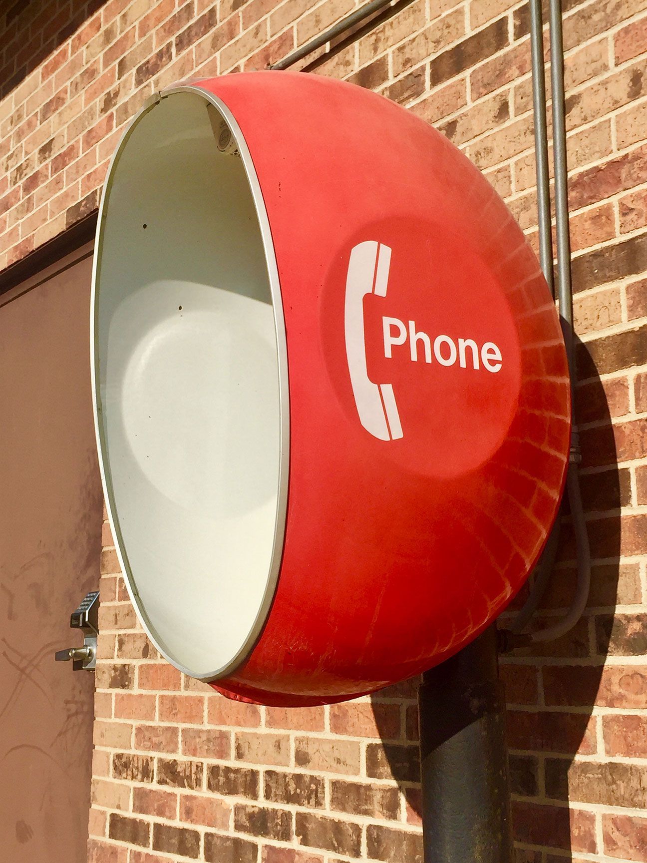 Red wall-mounted public phone booth on a brick building exterior