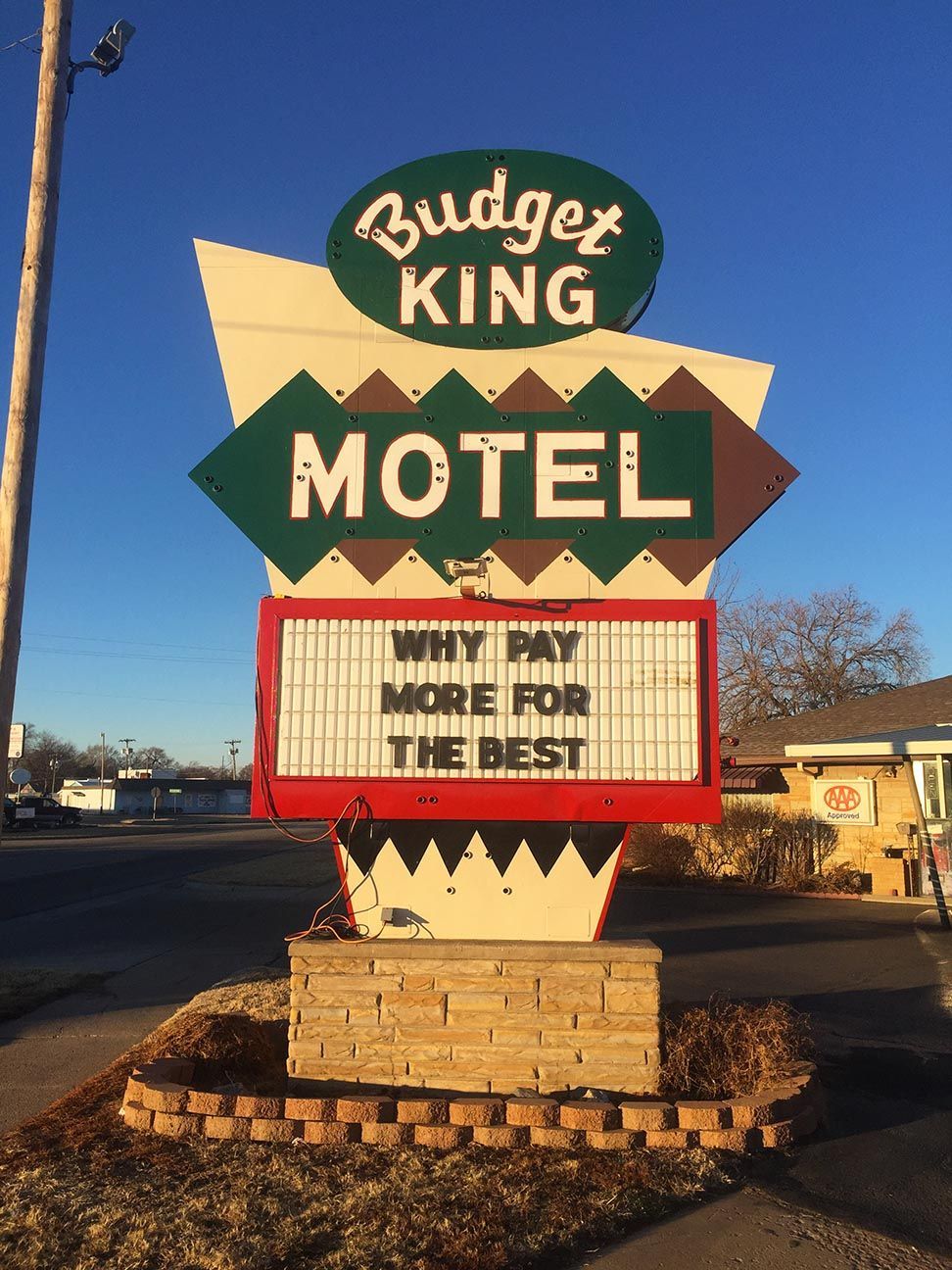 Budget King Motel roadside sign with green and tan retro lettering and a white message board at dusk