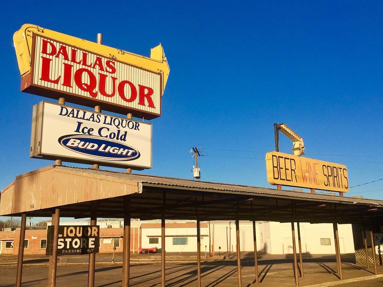 Old roadside liquor store with faded signs under a bright blue sky