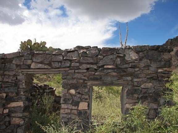 Stone wall ruins with two window openings under a cloudy blue sky