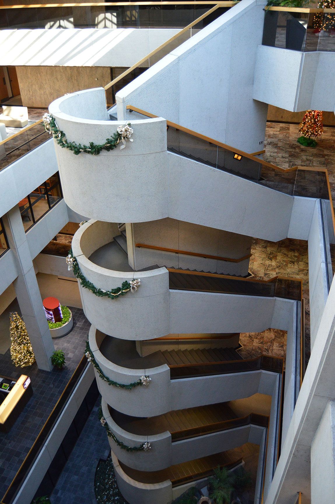 Exterior spiral staircase with curved white concrete walls and dark railings in a building courtyard