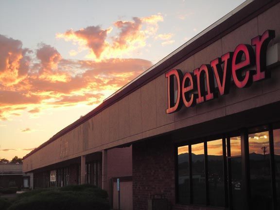 Denver building facade at sunset with pink-lit clouds and reflective windows