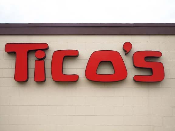 Red “Tico’s” sign on a beige brick wall