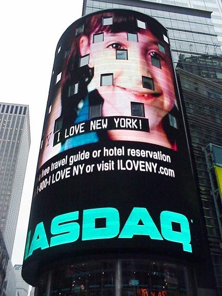 Curved digital billboard in Times Square with “I LOVE NEW YORK!” and “NASDAQ” text on screen.