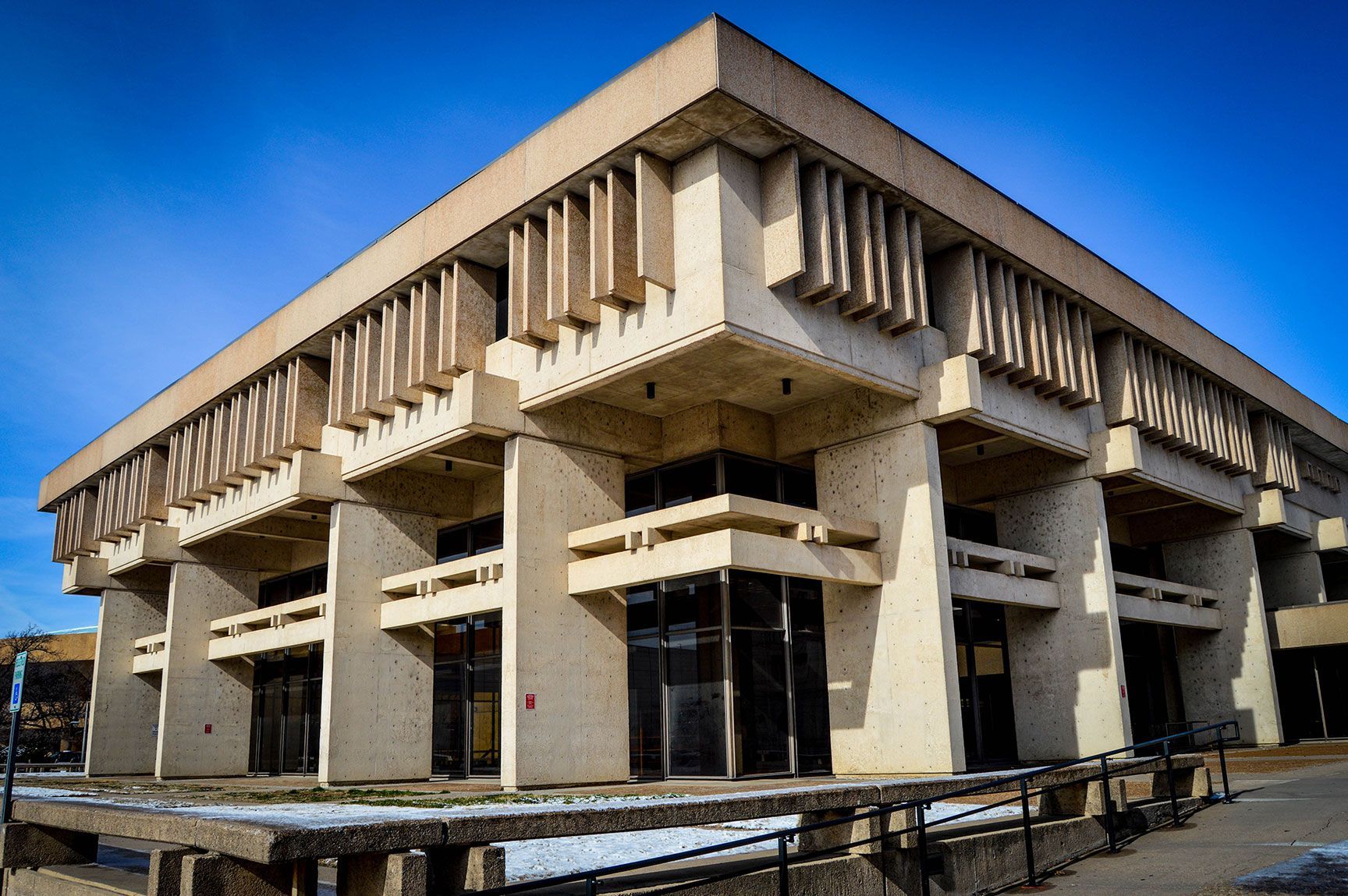 Concrete modern building with geometric overhangs and columns under a blue sky