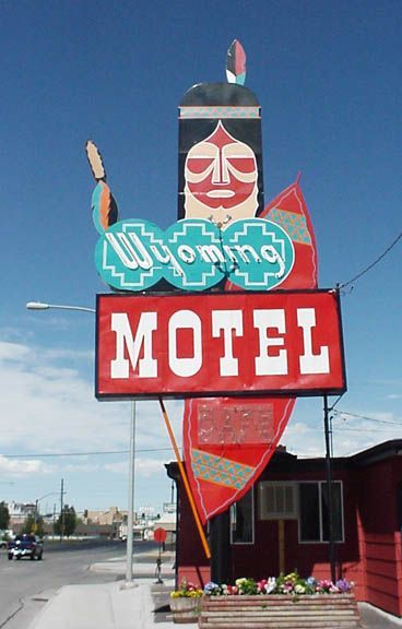 Colorful roadside motel sign with a red “MOTEL” panel and turquoise “Yummy” lettering under a blue sky