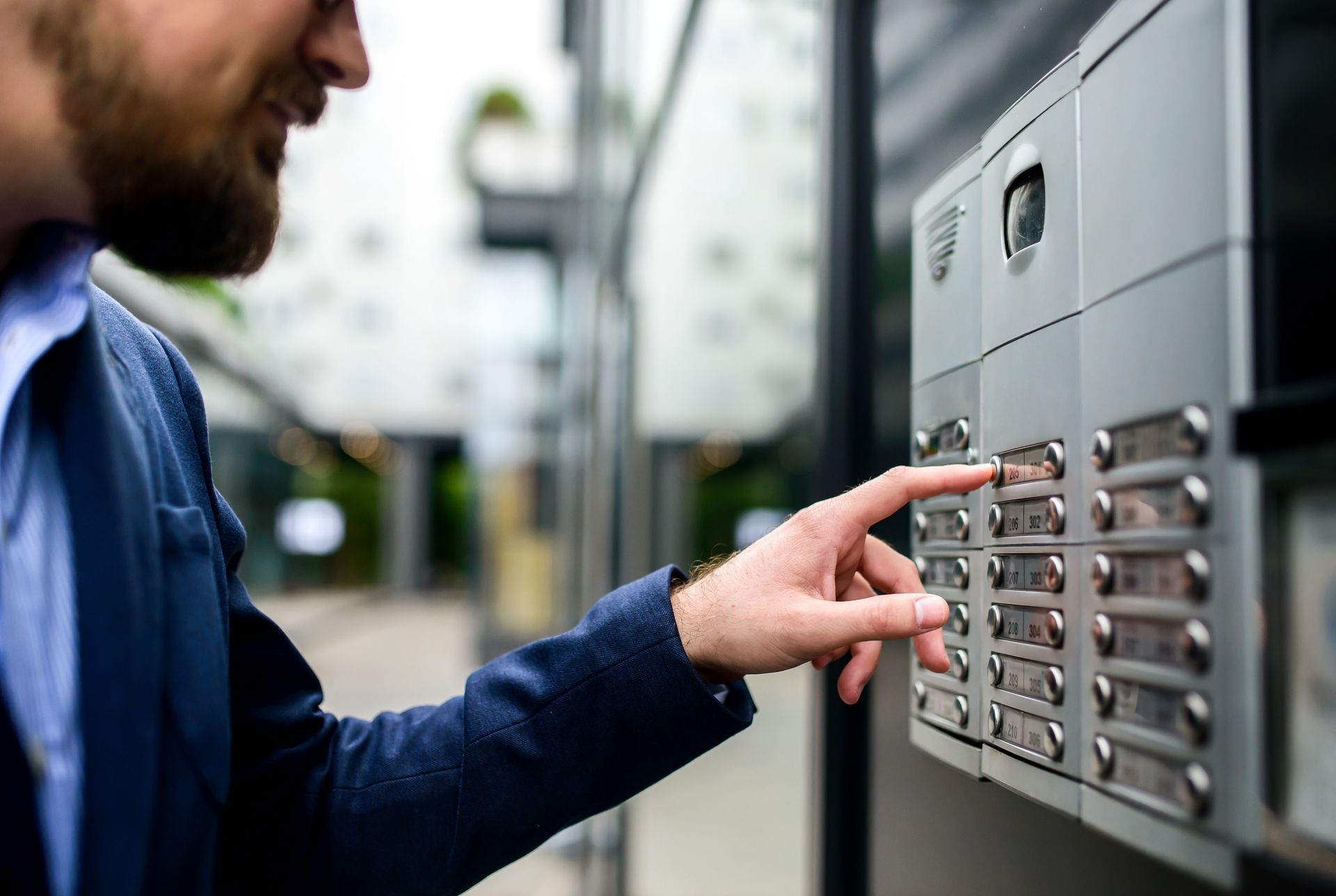 A man is pressing a button on a doorbell. A man is pressing a button on a doorbell.