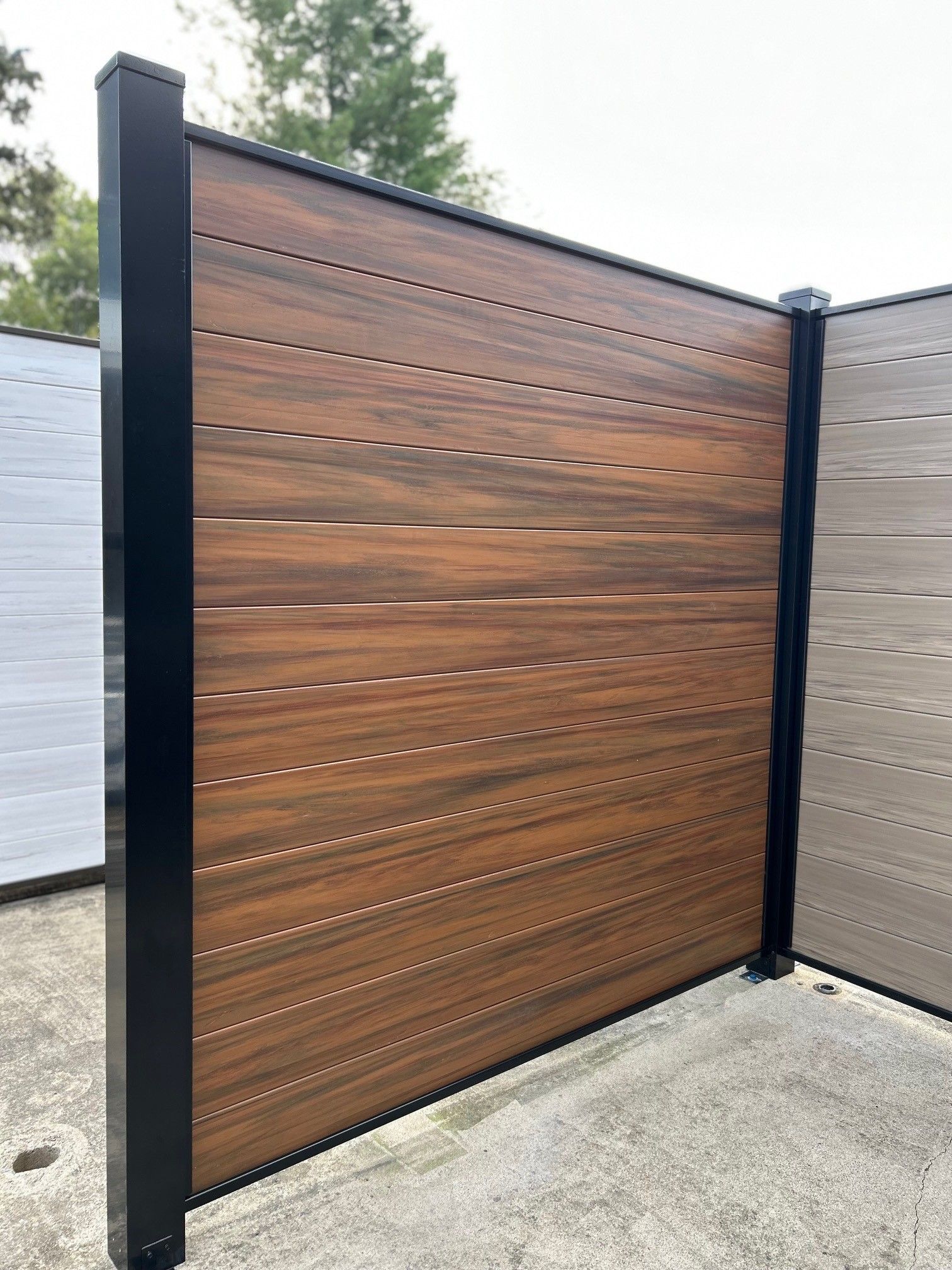 Brown composite privacy fence section with black posts.