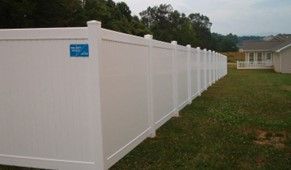 A long white fence in a grassy area A long white fence in a grassy area
