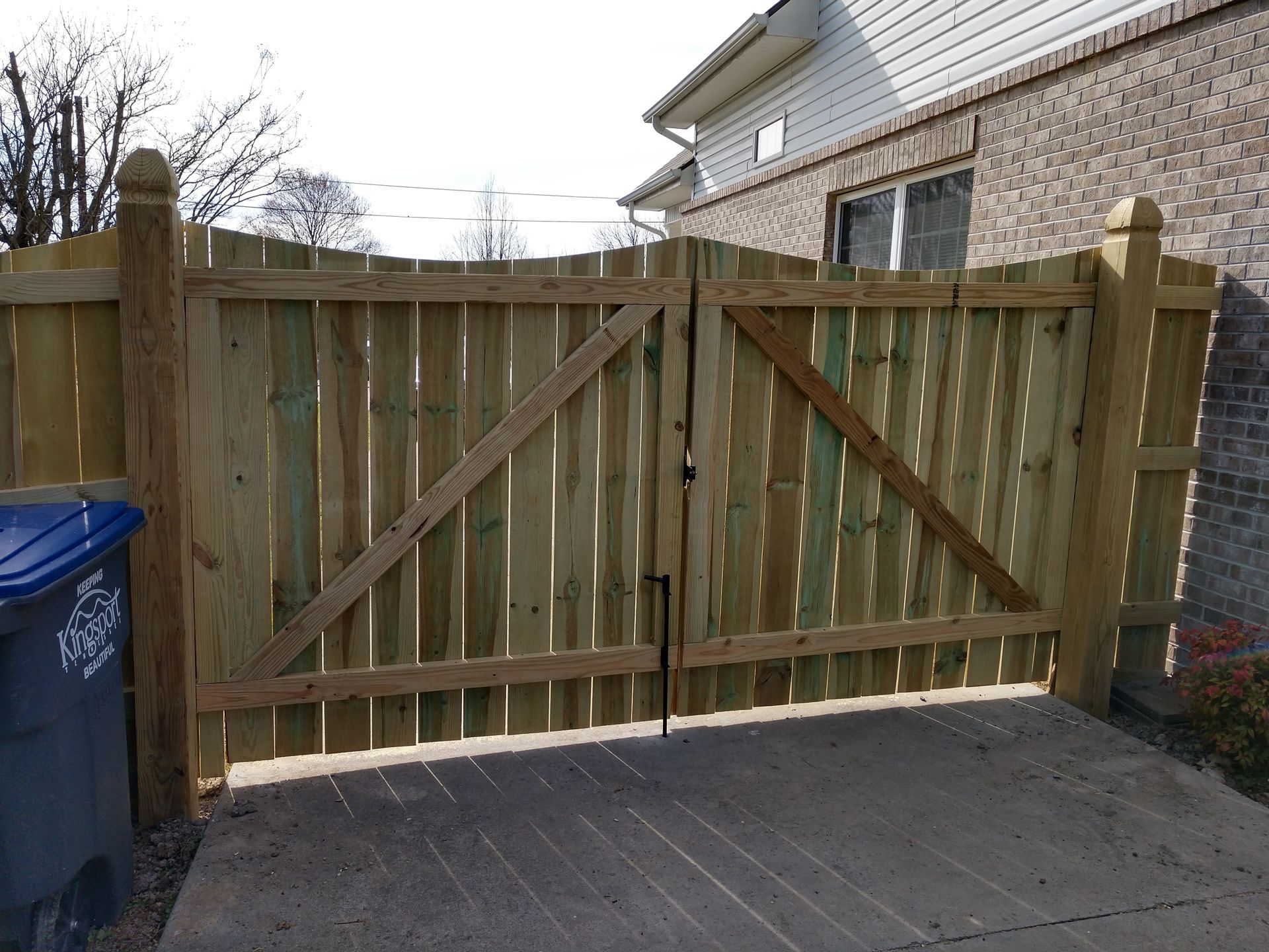 A wooden fence is sitting in front of a brick house. A wooden fence is sitting in front of a brick house.