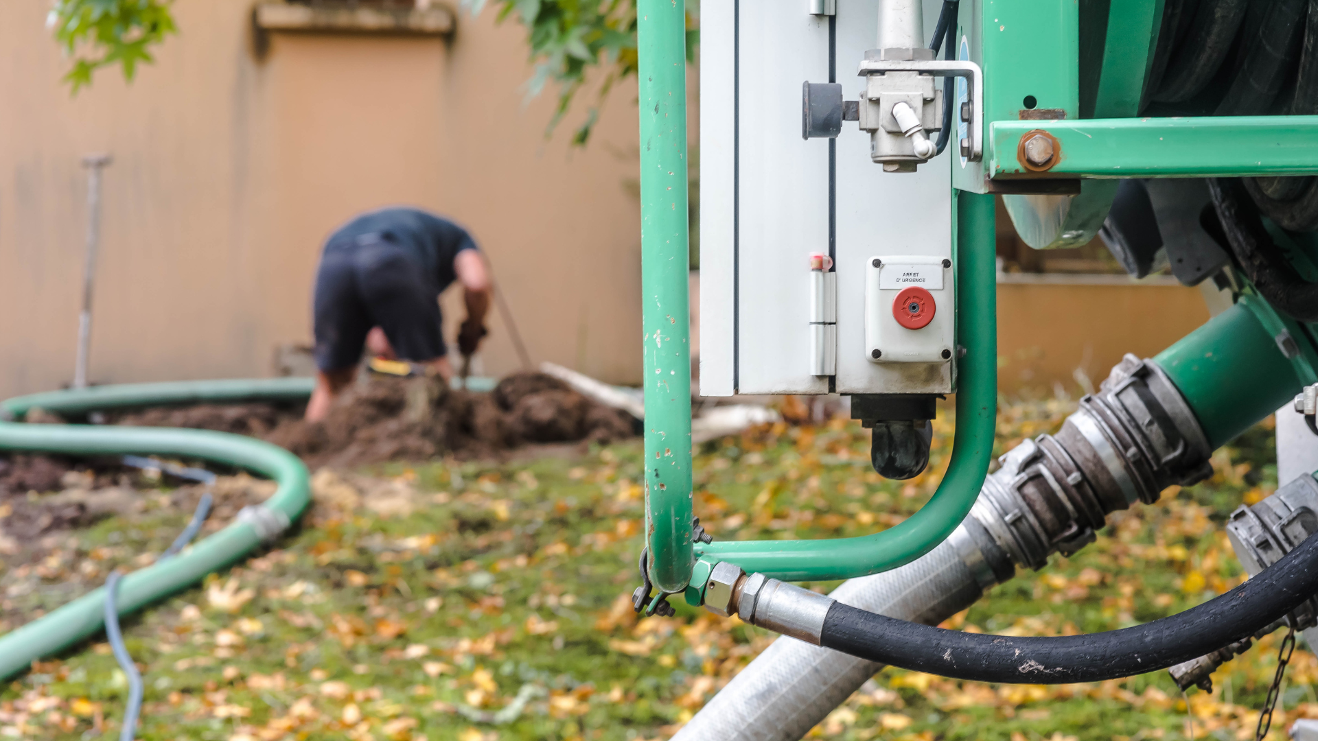 A man is digging a hole in the ground with a hose.