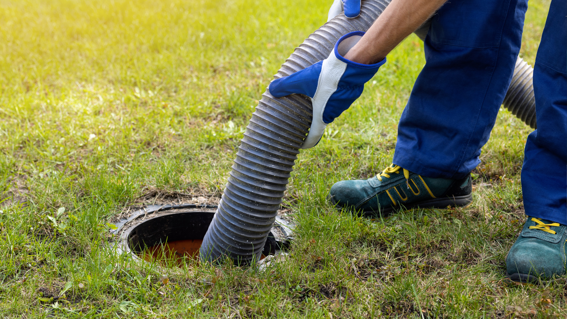 A man is pumping a hose into a septic tank.