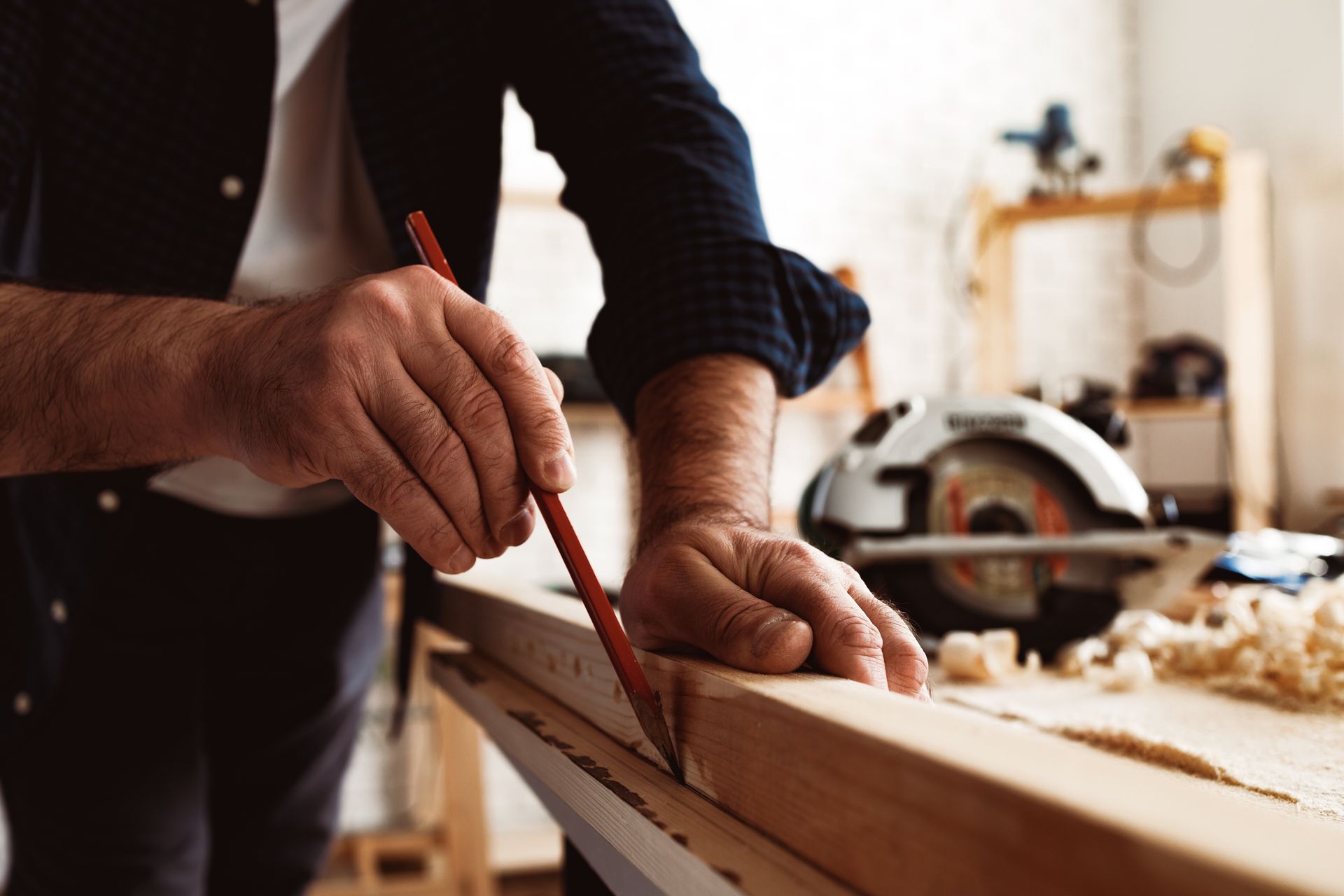 Un homme mesure un morceau de bois avec un crayon.