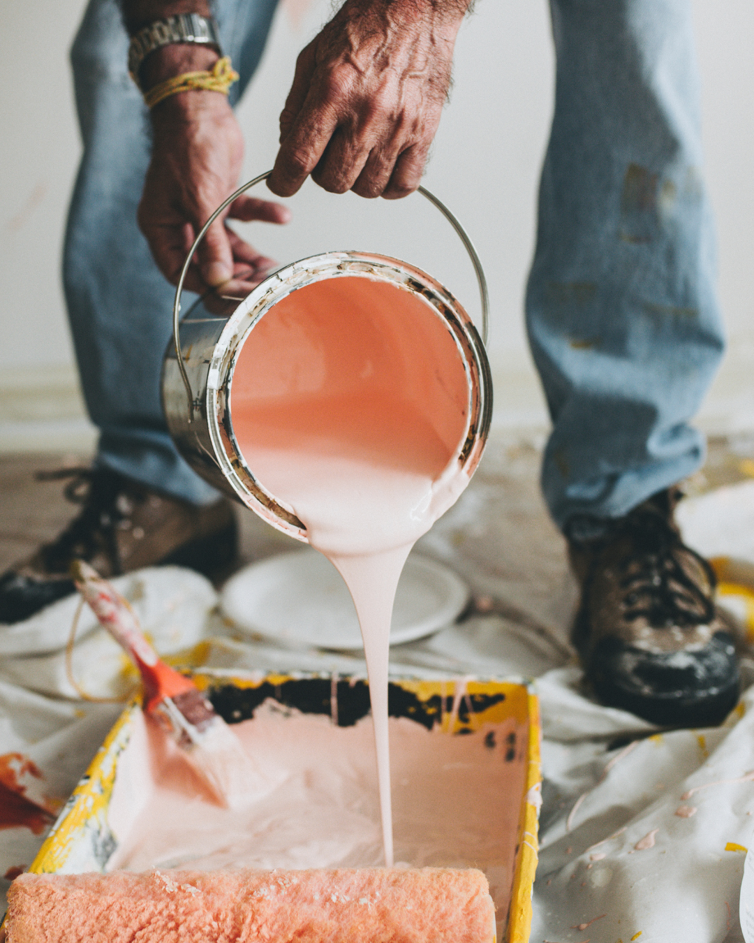 Un homme verse de la peinture rose dans un bac à peinture.