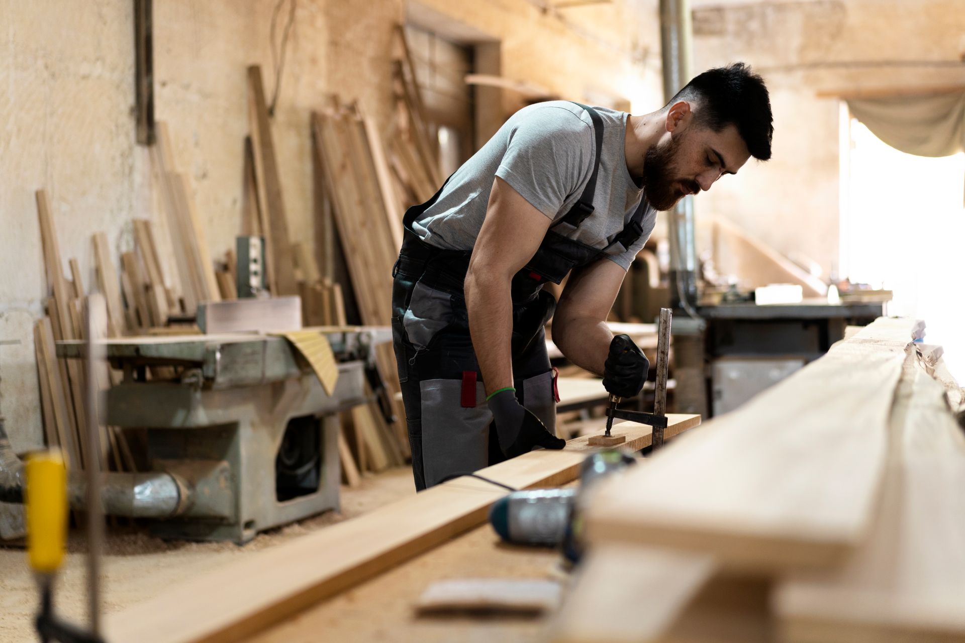 Un homme travaille sur un morceau de bois dans un atelier.