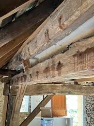 Une poutre ancienne en bois horizontal avec des trous.