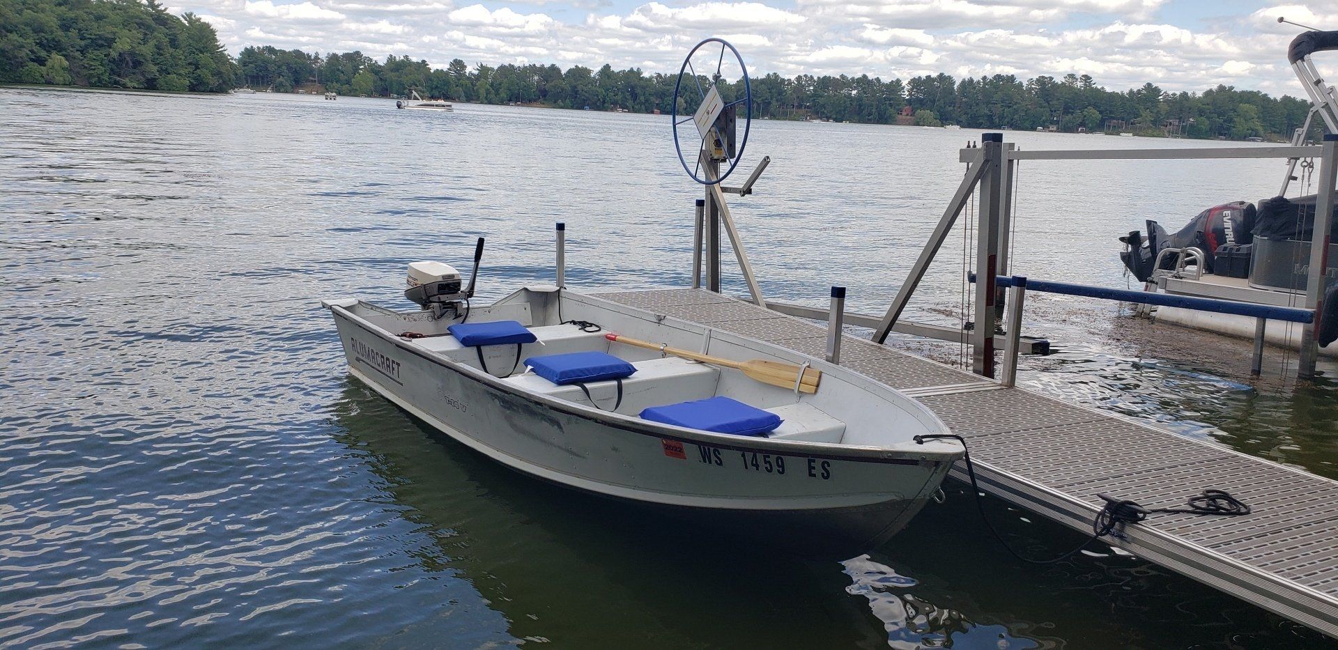 A small boat is docked at a dock on a lake.