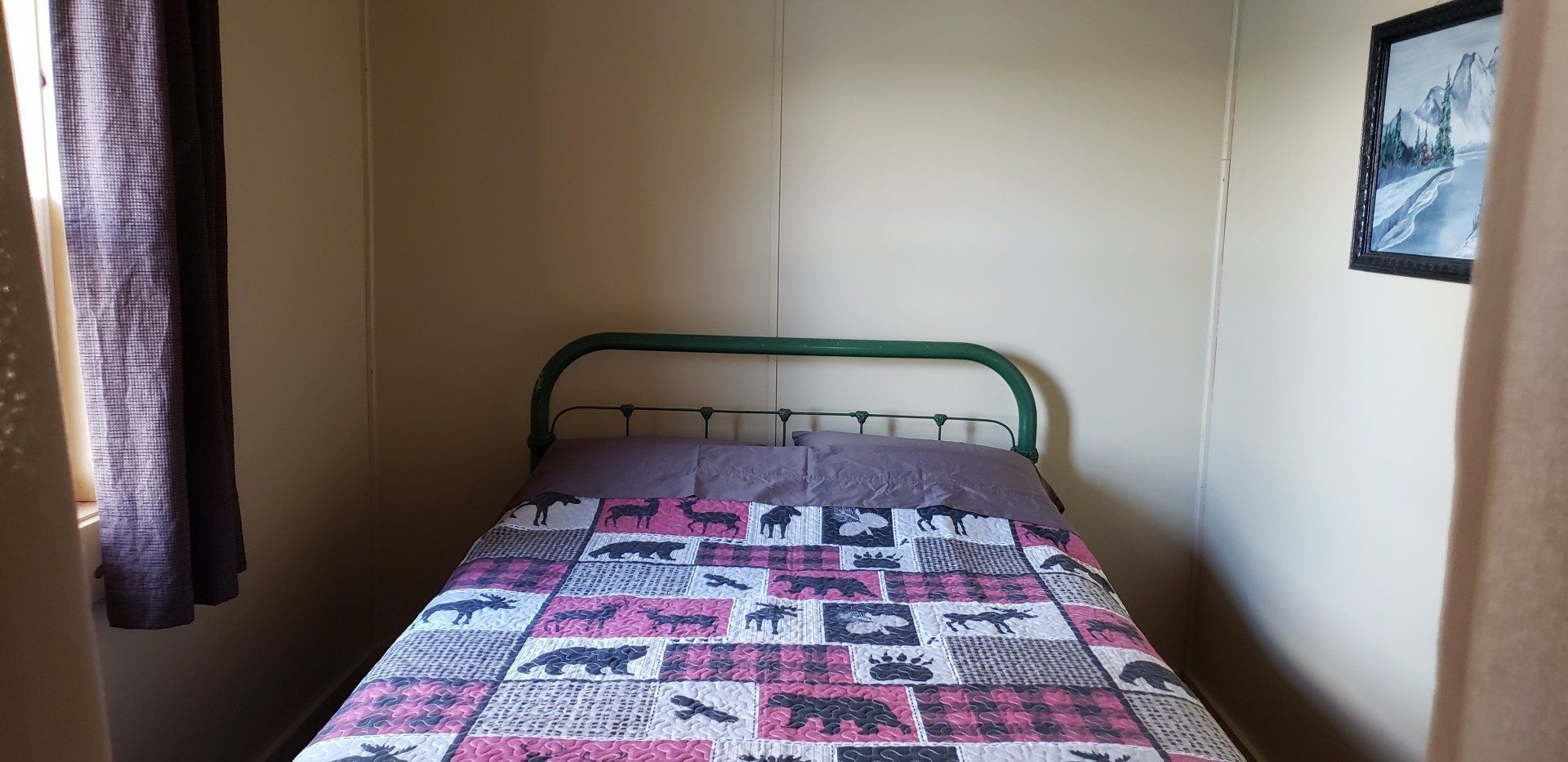 A bedroom with a bed and a picture on the wall.