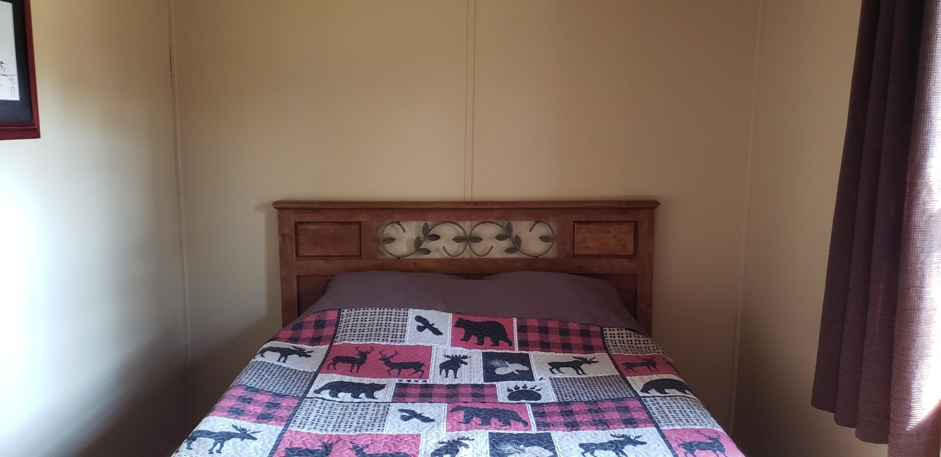 A bedroom with a bed and a window with a picture on the wall
