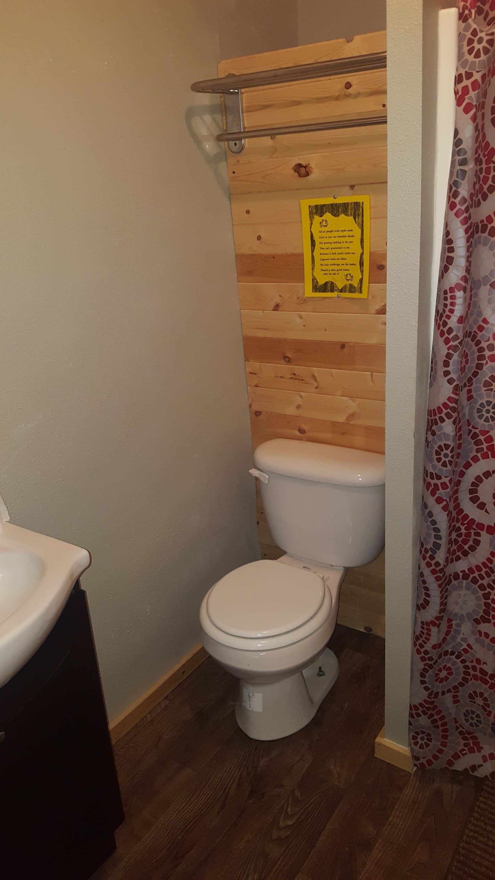 A bathroom with a toilet , sink and shower.