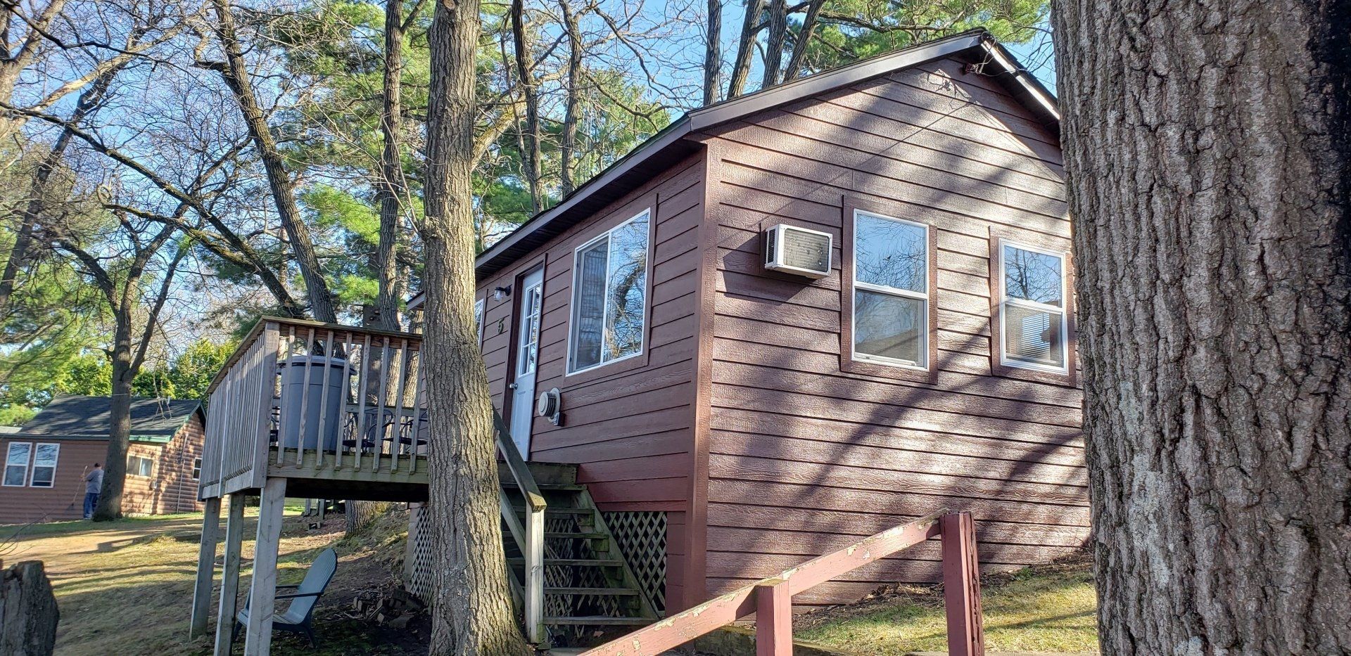 A small house with stairs leading up to it is surrounded by trees.