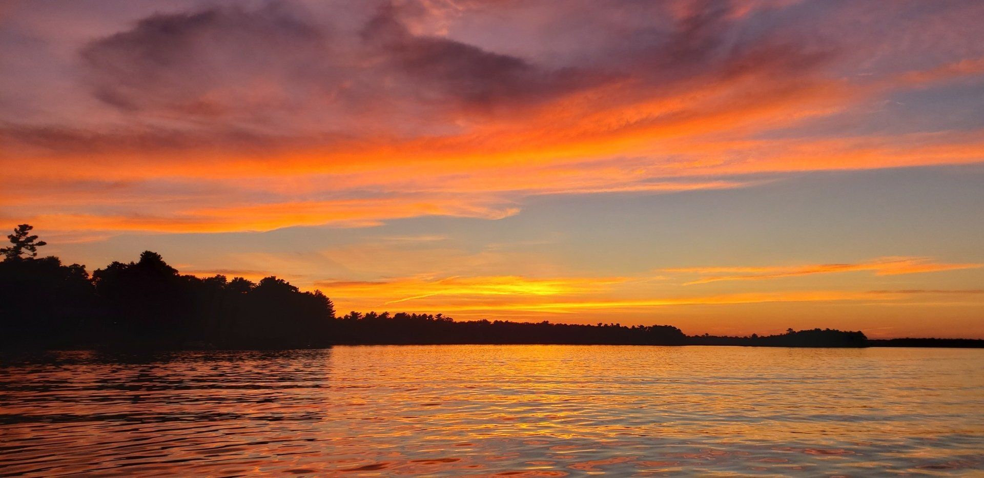 A sunset over a lake with trees in the background