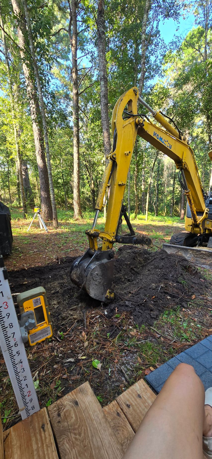 Yellow excavator digging earth near trees.
