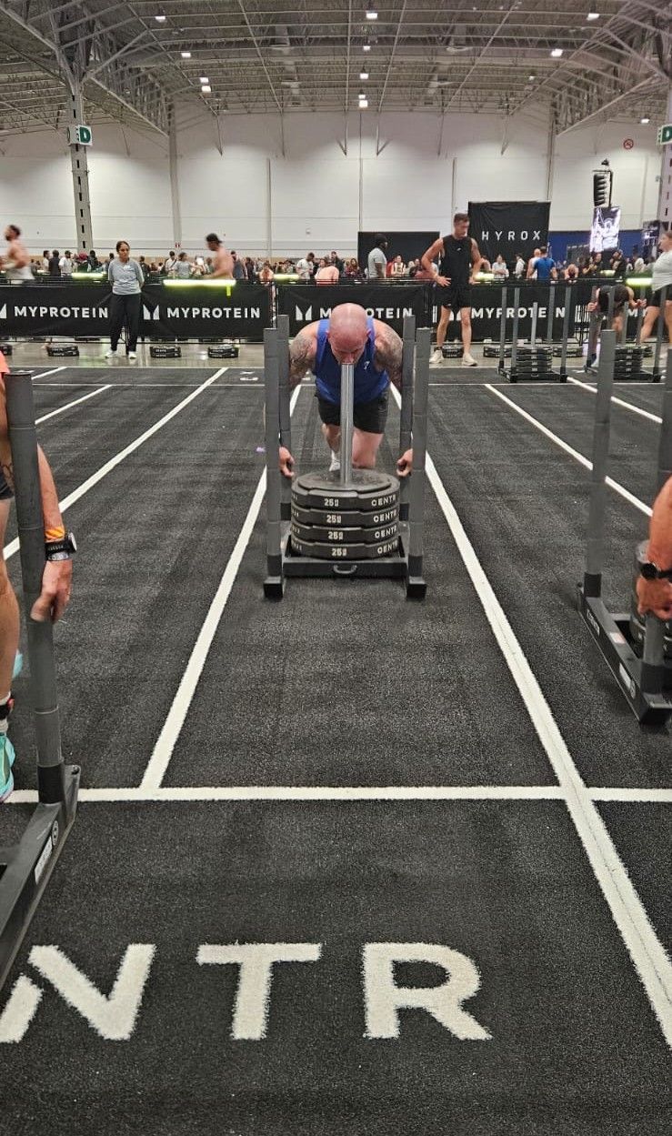 Athletes rowing hard in a HYROX indoor race, focused and sweating in a packed gym setting