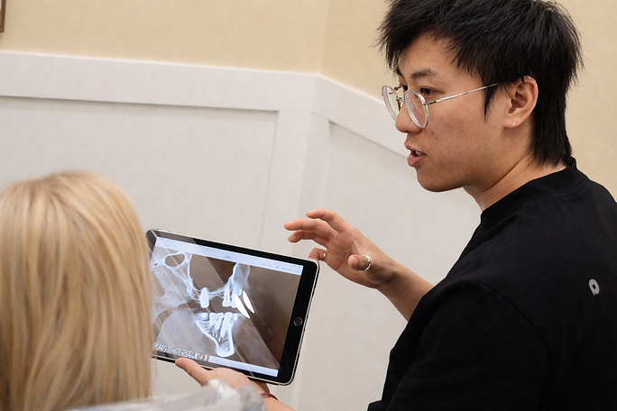 Person in black shirt pointing at a laptop screen during a consultation in a small office