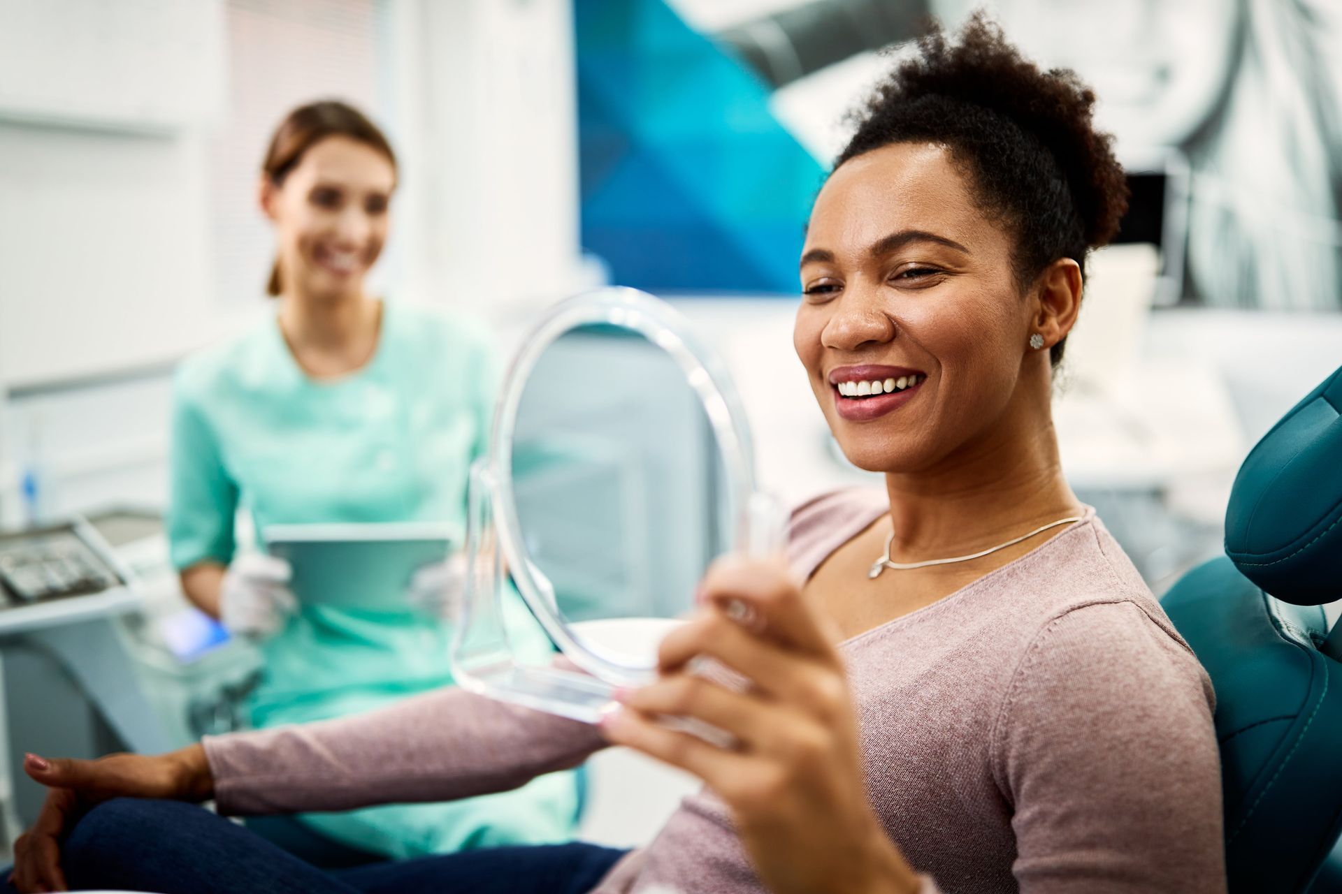 Patient smiling in a dental chair while a dentist stands nearby with tools.