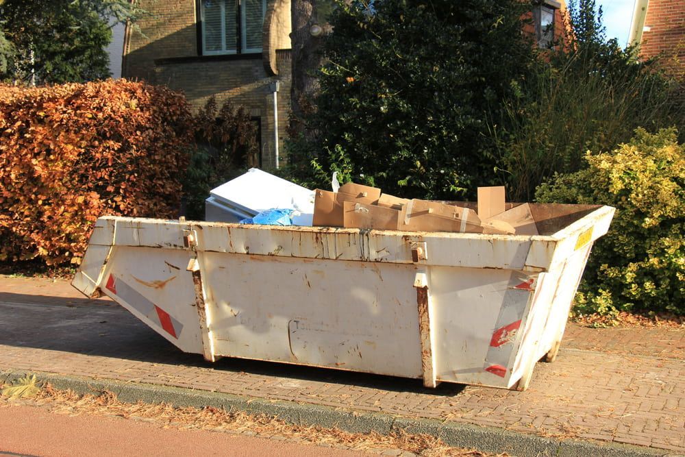 White dumpster filled with cardboard boxes on a sidewalk. — Swift Skips in Kilkivan, QLD
