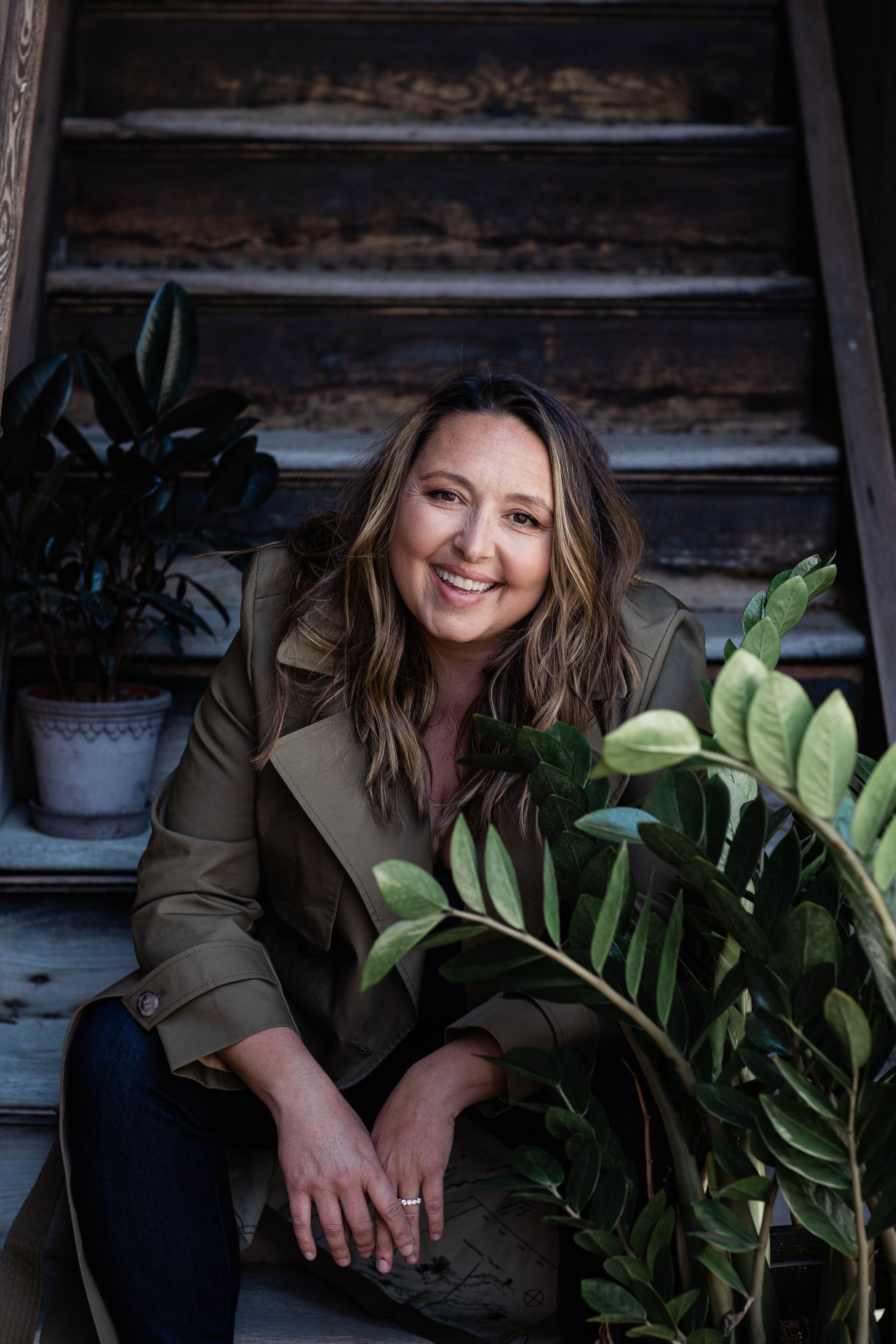 Jess sitting down on steps by a green plant